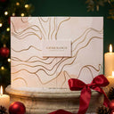 Coffret fermé du Calendrier de l'Avent 2026 Gemology – design aquarelle rose et or, finition marquée à chaud, ambiance Noël